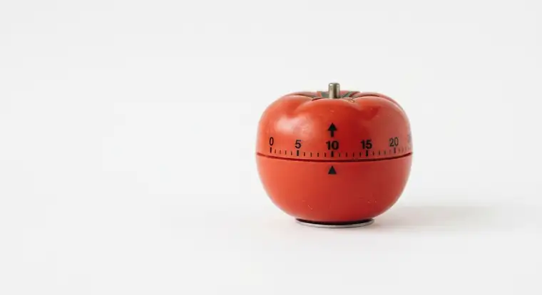 Osoba pracuje z timerem Pomodoro na biurku, planuje sesje pracy i przerwy, aby utrzymać długotrwałą motywację i produktywność